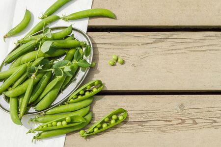Pods of fresh green peas on an old wooden table.の写真素材