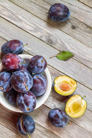 Ripe blue plums in a round white bowl.の写真素材