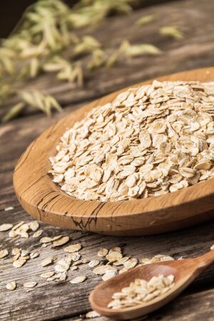 Organic oat flakes on a wooden plate.の写真素材