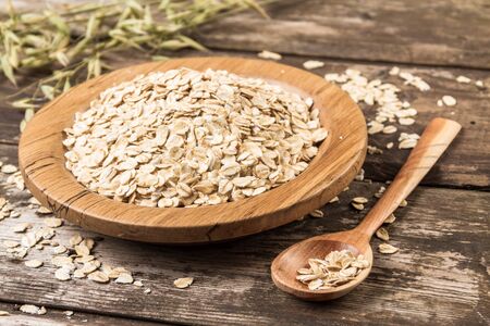Organic oat flakes on a wooden plate.の写真素材
