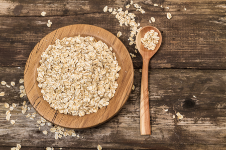 Organic oat flakes on a wooden plate.の写真素材