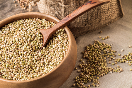 Raw organic buckwheat grains in a wooden bowl on a wooden table.の写真素材
