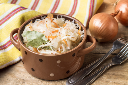 Organic homemade sauerkraut in a bowl and fresh onions on a wooden table.の写真素材
