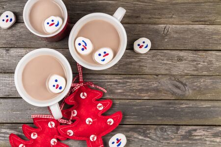 Cups of hot cocoa and Christmas marshmallow snowmen on a gray wooden background.の写真素材