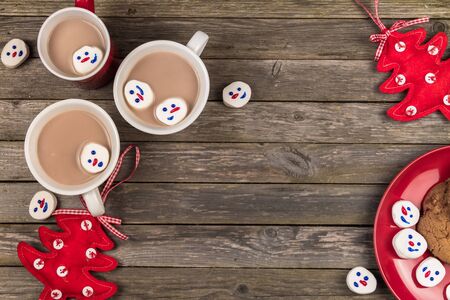 Cups of hot cocoa, Christmas marshmallow snowmen and home made cookies on a gray wooden background.の写真素材