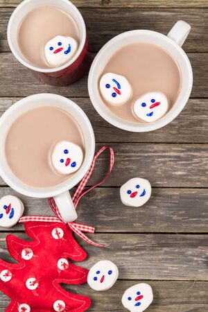 Cups of hot cocoa and Christmas marshmallow snowmen on a gray wooden background.の写真素材