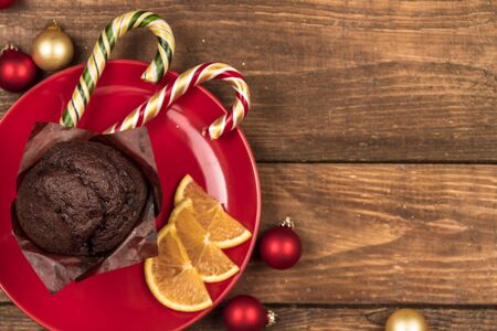 Chocolate cake, Christmas candy canes  and slises of orange on a red plate.の写真素材