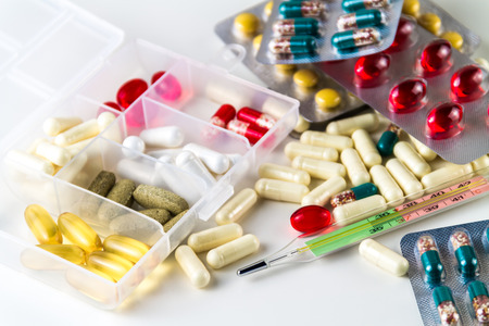 Various medical color capsules, pills and thermometer on a white background.の写真素材