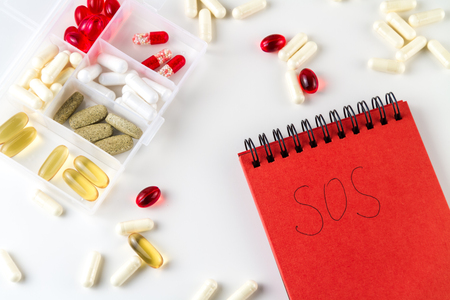 Various medical color capsules, pills and notebook for records on a white background.の写真素材