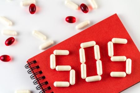 Various medical capsules, pills and word "SOS".の写真素材