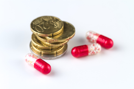 Medical capsules and coins on a white background.の写真素材
