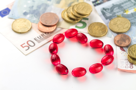 Medical capsules, money and coins on a white background.の写真素材