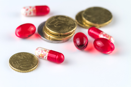 Medical capsules and coins on a white background.の写真素材