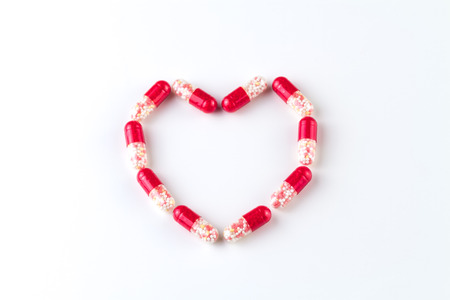 Medical capsules lie with a shape of heart on a white background.の写真素材