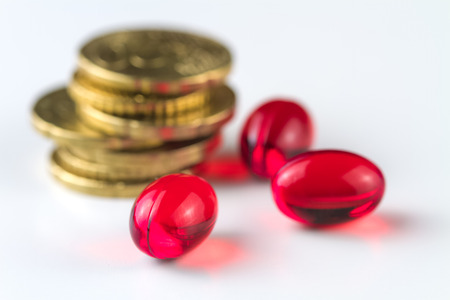 Medical capsules and coins on a white background.の写真素材