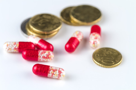 Medical capsules and coins on a white background.の写真素材