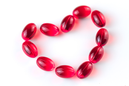 Medical red capsules lie with a shape of heart on a white background. Close up.の写真素材