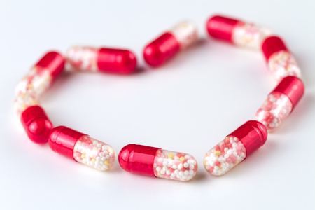Medical capsules lie with a shape of heart on a white background.の写真素材
