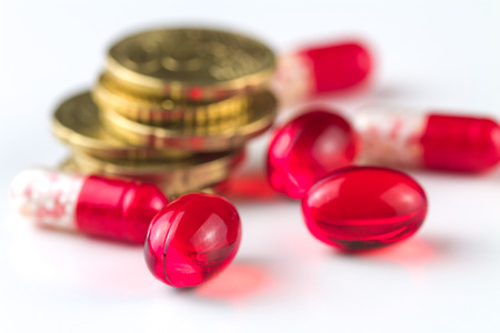 Medical capsules and coins on a white background.の写真素材