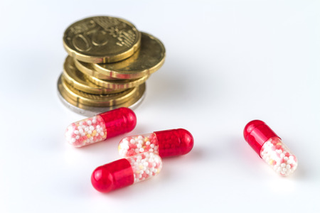 Medical capsules and coins on a white background.の写真素材
