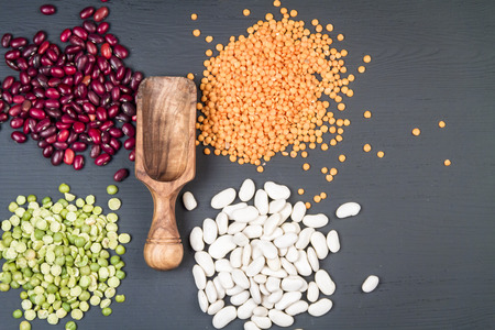 Natural white and red beans, red lentil and green peas on a black background.の写真素材