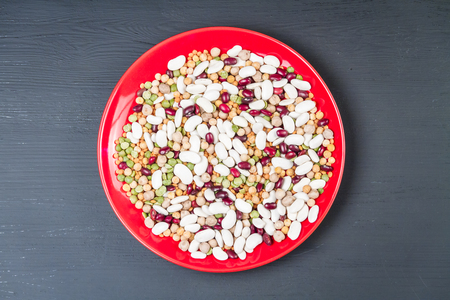 Mix of natural organic chickpeas, white and red beans, red lentil, green and yellow peas on a plate.の写真素材