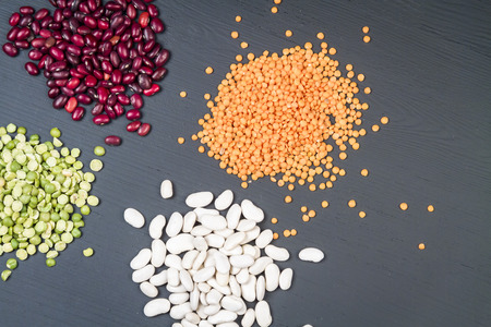 Natural white and red beans, red lentil and green peas on a black background.の写真素材