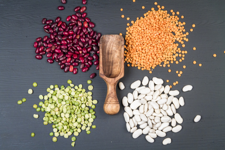 Natural white and red beans, red lentil and green peas on a black background.の写真素材