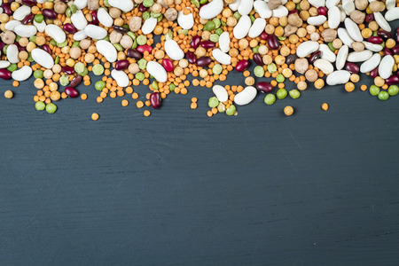 Mix of natural organic chickpeas, white and red beans, red lentil, green and yellow peas on a black background.の写真素材