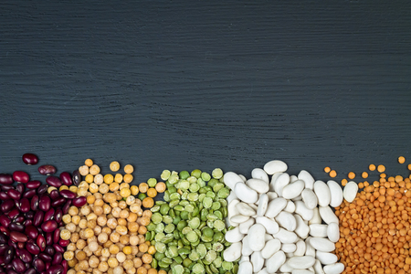 Natural organic chickpea, white and red beans, red lentil, green and yellow peas on a black background.の写真素材