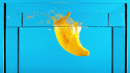Falling fruit. Painted in the color of fruit in the water on a blue background in the aquariumの写真素材