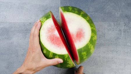 We cut the watermelon into small square pieces with a knife.の写真素材