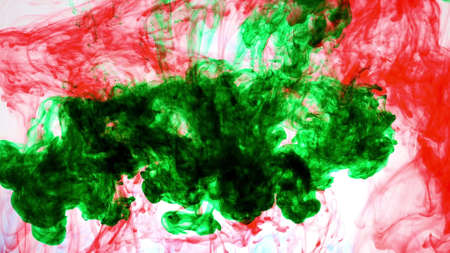 An explosion of colored paints in water on a white backgroundの写真素材