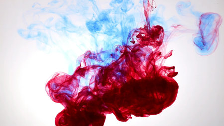 An explosion of colored paints in water on a white backgroundの写真素材