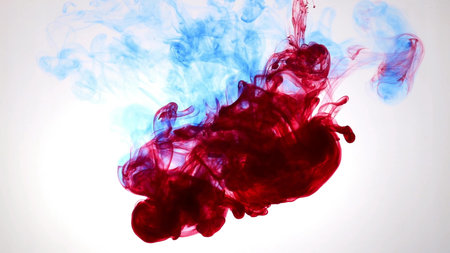An explosion of colored paints in water on a white background