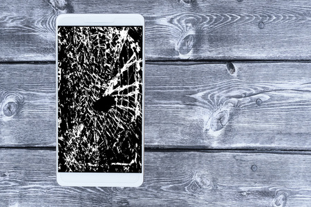 Smartphone with a broken screen on a wooden background.の写真素材