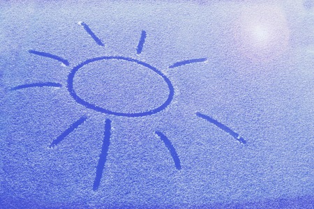 frozen glass of a car on a winter day, a drawing of the sun.の写真素材