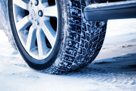 Close up of a cars tires on a snowy road.の写真素材