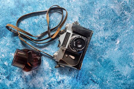 Vintage film camera and 35mm film on blue background.の写真素材