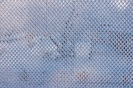 Part of the fence made of metal wire covered with frost . Fence covered with hoarfrost on a frosty winter day.の写真素材