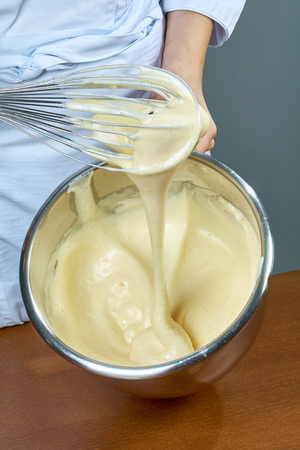 chef whips yellow cream in a bowl by hand for making cheesecakesの写真素材