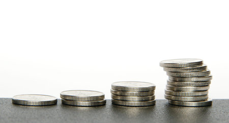 Rows of coins on dark surface with reflection