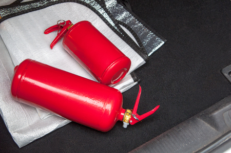 Trunk of the car in which there is a fire extinguishers with copyspace.  Two red tank of fire extinguisher inside car on windshield sun shade. Big and small red fire extinguishers in the car to prevent emergencies. Fire extinguishers for car safety.の写真素材