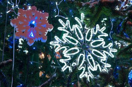 Bright glowing big LED and small foam snowflakes  on Christmas tree at night. Beautiful christmas decoration in the city. Christmas and new year holiday concept.の写真素材