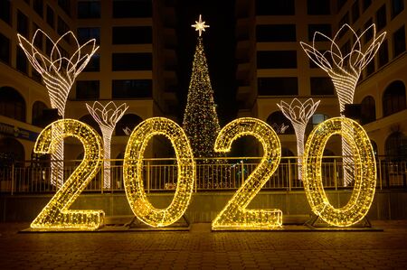 Illuminated numbers 2020 for New Year in the city at night. Christmas tree with a luminous star on the top.の写真素材
