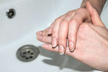 Dirt under the nails of a woman. Women's hands are in poor condition and require care. Dirty female hands after gardening above the sink.  Beauty industry, nail and hands care concept.の写真素材