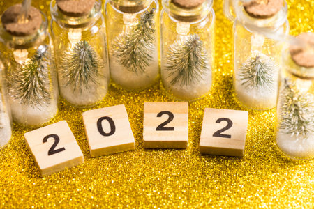New Year 2022 theme. Golden shiny surface, decorative bottles sealed with a cork stopper with...