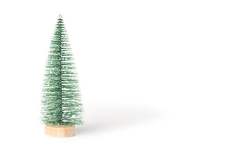 Green vintage bottle brush Christmas tree on a white background.  Miniature Christmas tree in the shape of a triangular brush on a wooden round stand. Front view. Copy space for holiday text.の写真素材