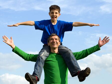 a man is handing his happy son outdoorsの写真素材