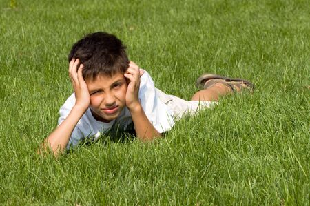 a disappointed teenager is lying in the green grassの写真素材